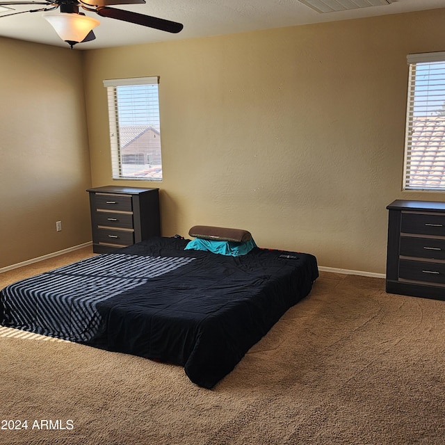 carpeted bedroom with multiple windows and ceiling fan