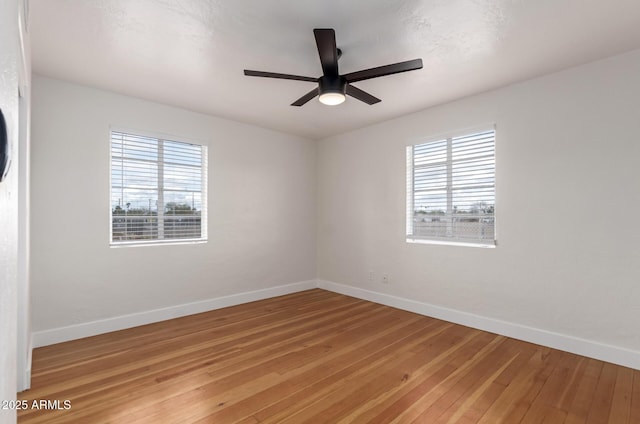 empty room featuring a healthy amount of sunlight, baseboards, light wood-style floors, and a ceiling fan