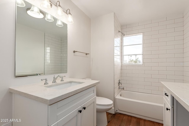 full bath with toilet,  shower combination, wood finished floors, and vanity