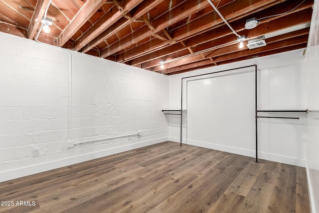 unfinished basement featuring wood finished floors and concrete block wall