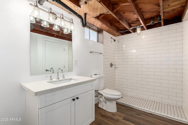 bathroom featuring vanity, toilet, wood finished floors, and a tile shower