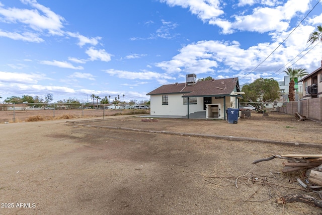 back of house with central AC unit, fence, and a shingled roof