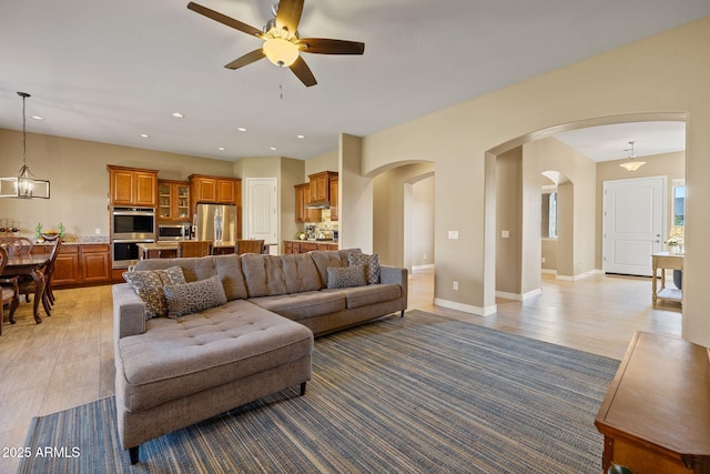 living room featuring arched walkways, a ceiling fan, recessed lighting, and baseboards