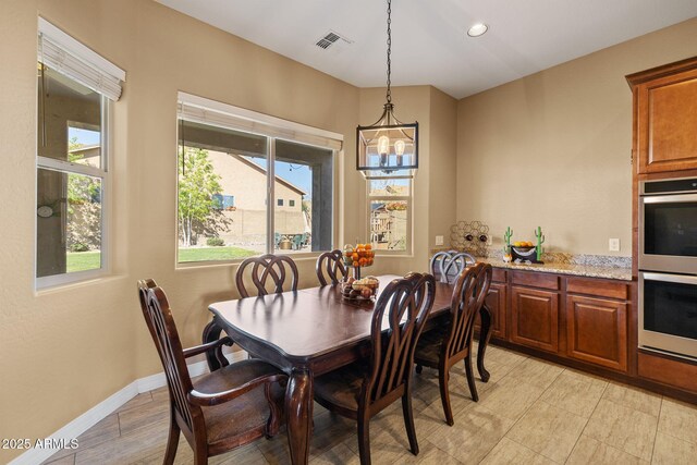 dining room with visible vents, baseboards, plenty of natural light, and a notable chandelier