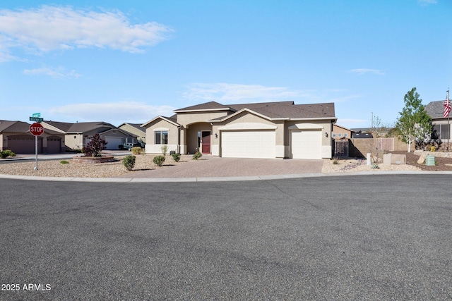 ranch-style home featuring fence, a residential view, an attached garage, stucco siding, and decorative driveway