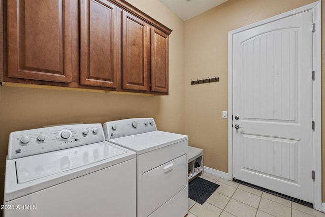 laundry area with baseboards, light tile patterned flooring, cabinet space, and washing machine and clothes dryer
