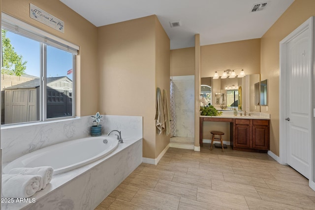 full bathroom with visible vents, walk in shower, a garden tub, and vanity