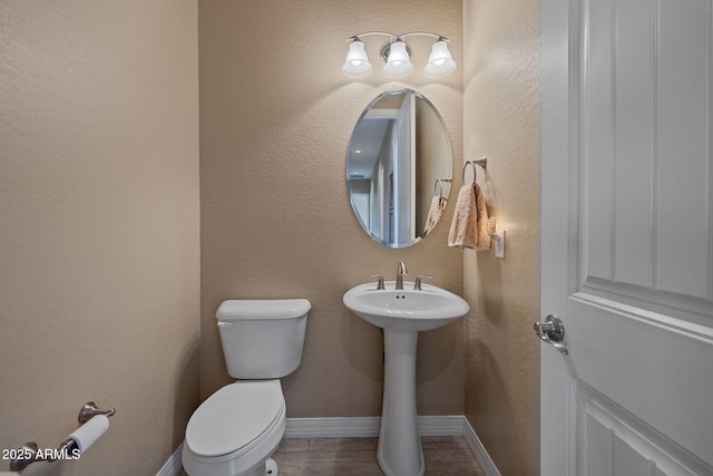half bathroom featuring baseboards, a sink, and toilet
