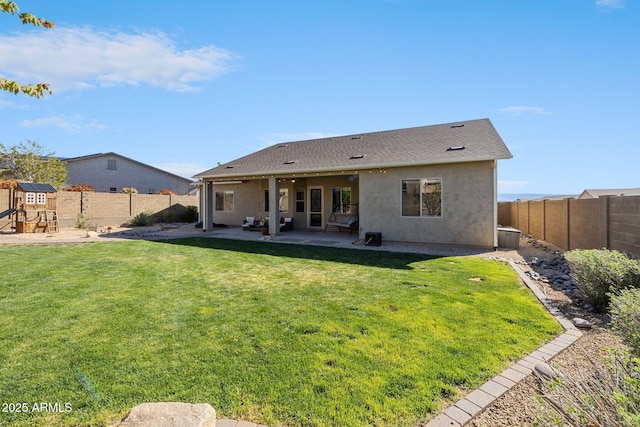 back of property with a fenced backyard, a patio area, and a yard