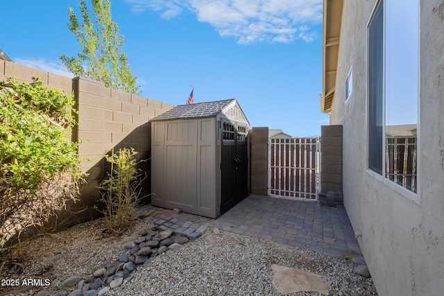 view of patio featuring fence, a storage unit, an outdoor structure, and a gate