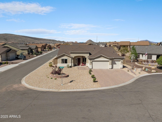 ranch-style home with stucco siding, an attached garage, a mountain view, driveway, and a residential view