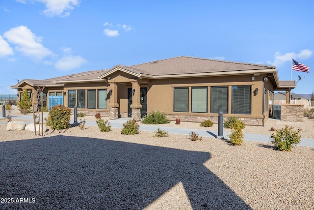 view of front facade with stucco siding, a tile roof, and stone siding