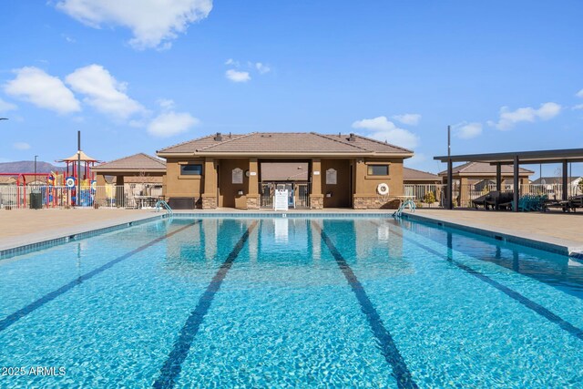 pool with a patio area, fence, and playground community