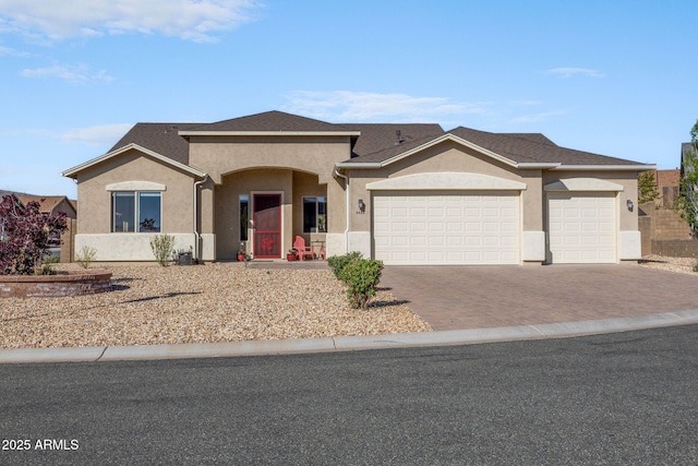 single story home with a garage, stucco siding, and decorative driveway