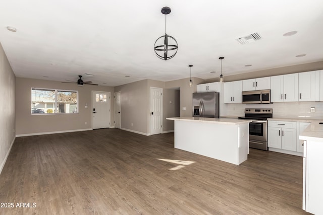 kitchen with pendant lighting, ceiling fan with notable chandelier, stainless steel appliances, and white cabinetry