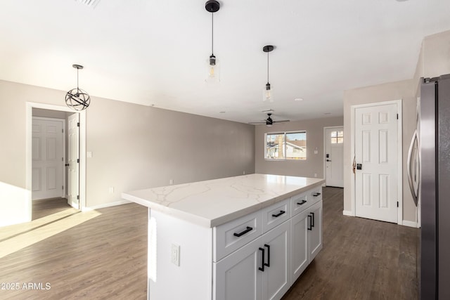 kitchen featuring ceiling fan, a center island, white cabinetry, hanging light fixtures, and stainless steel refrigerator