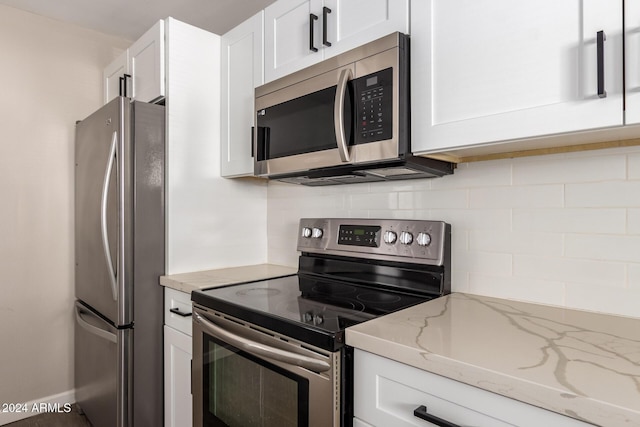 kitchen featuring backsplash, light stone counters, white cabinetry, and stainless steel appliances