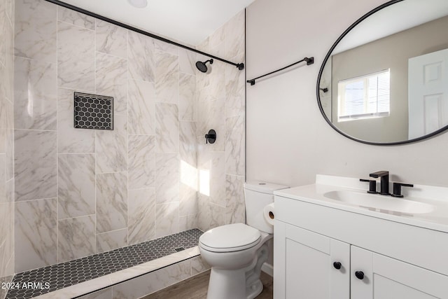 bathroom with a tile shower, vanity, and toilet