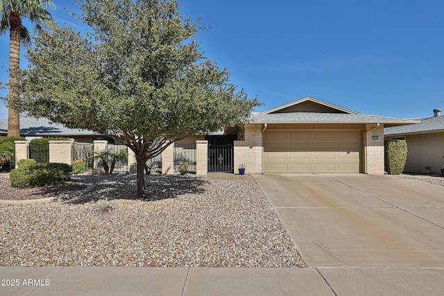 view of front of house with a garage, concrete driveway, a gate, fence, and brick siding