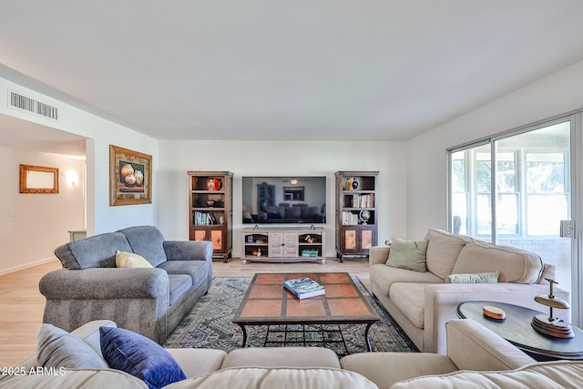 living room with light wood-type flooring, baseboards, and visible vents