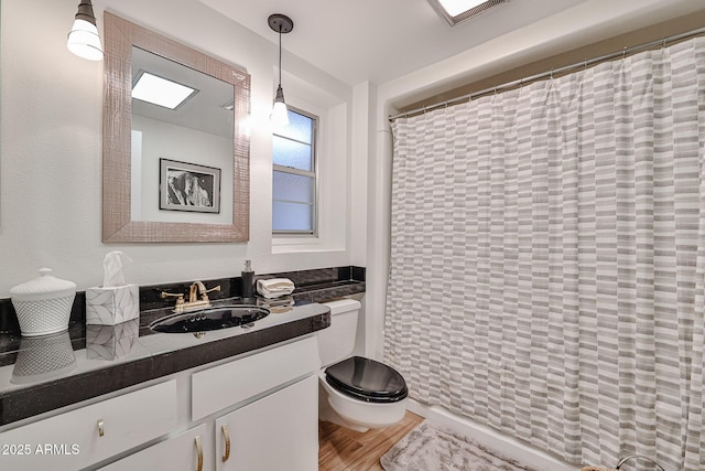 bathroom with curtained shower, visible vents, toilet, vanity, and wood finished floors