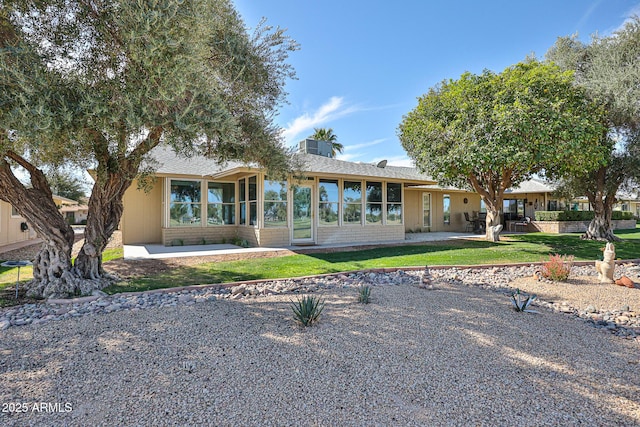 rear view of property featuring a lawn, a patio area, and a sunroom