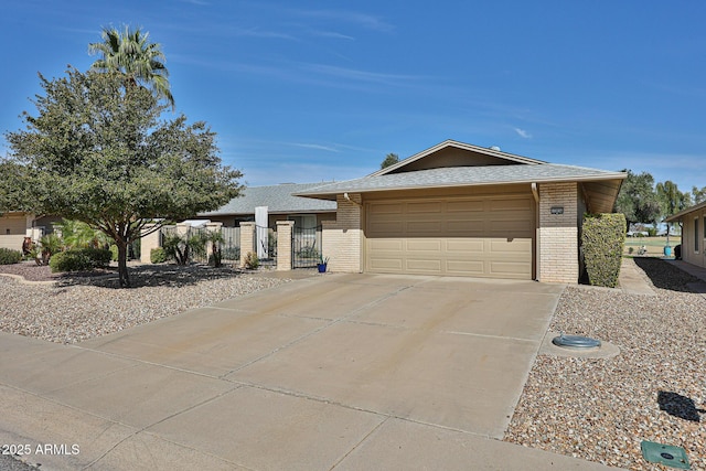 ranch-style house featuring brick siding, a shingled roof, concrete driveway, an attached garage, and fence