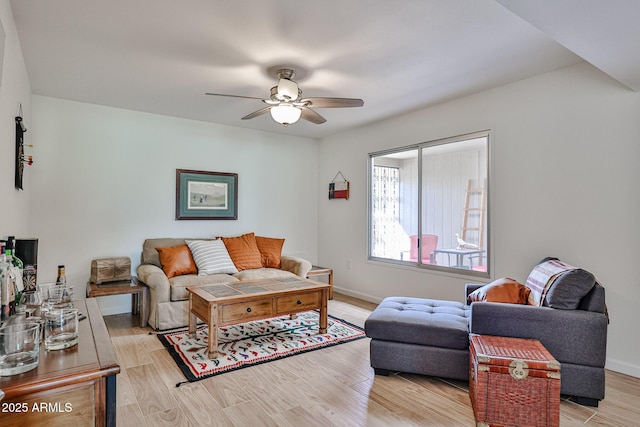 living room with a ceiling fan, light wood-style flooring, and baseboards