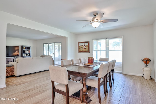 dining room featuring light wood finished floors, ceiling fan, and baseboards