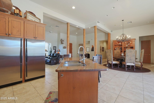 kitchen featuring light tile patterned floors, stainless steel refrigerator, pendant lighting, ceiling fan with notable chandelier, and sink