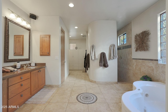 bathroom with plenty of natural light, a tub to relax in, vanity, and tile patterned flooring