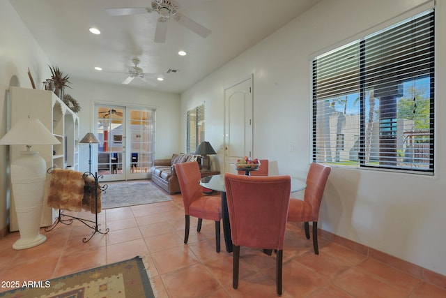 tiled dining space featuring ceiling fan, a healthy amount of sunlight, and french doors