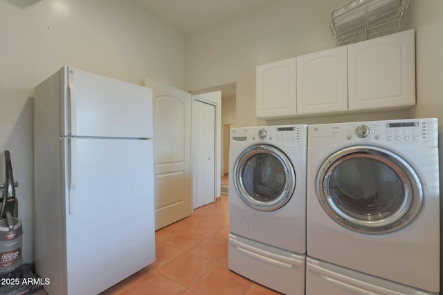 clothes washing area featuring washer and clothes dryer, light tile patterned flooring, and cabinets