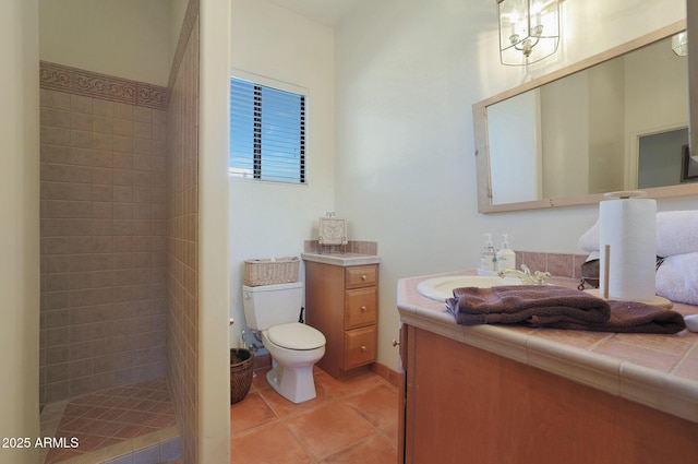 bathroom featuring tile patterned floors, vanity, a tile shower, and toilet