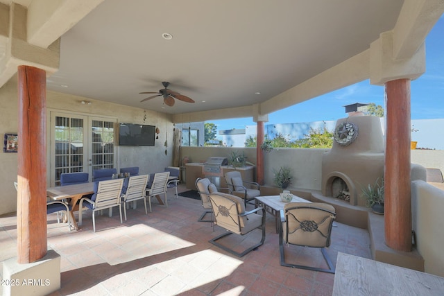 view of patio / terrace featuring ceiling fan, exterior kitchen, and exterior fireplace