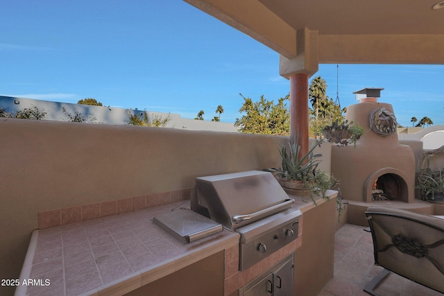 view of patio / terrace with exterior kitchen, exterior fireplace, and grilling area