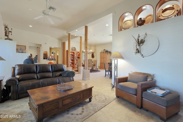 tiled living room with ceiling fan with notable chandelier