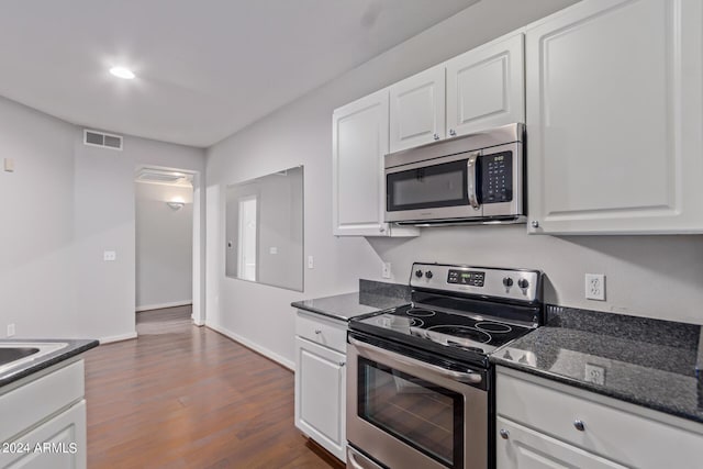 kitchen with white cabinets, dark hardwood / wood-style flooring, stainless steel appliances, and dark stone counters