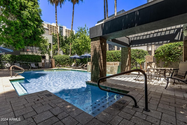 view of swimming pool with pool water feature and a patio