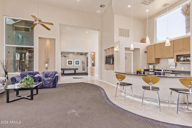 kitchen featuring a kitchen breakfast bar, a towering ceiling, ceiling fan, and light tile patterned flooring