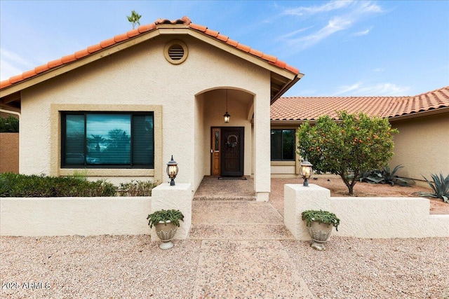 mediterranean / spanish house featuring a tile roof and stucco siding