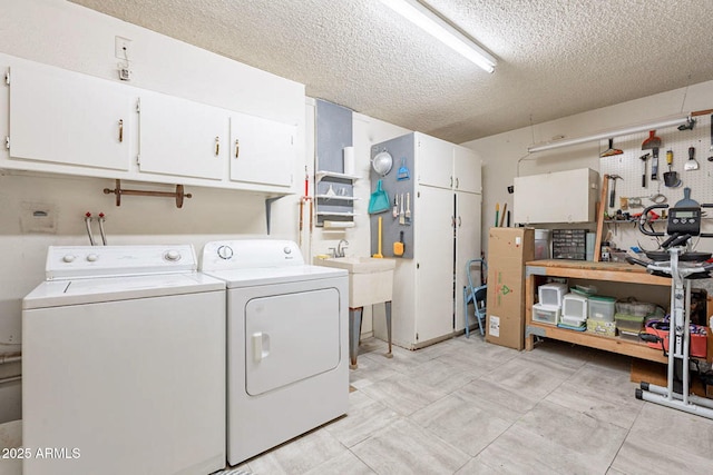 washroom with cabinets, a textured ceiling, washer and clothes dryer, and a workshop area