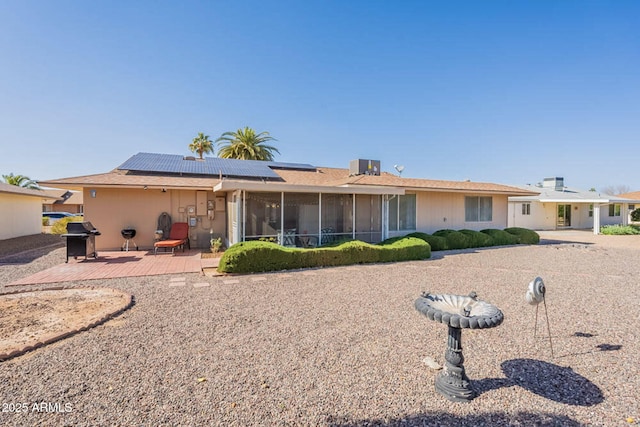 rear view of house featuring a sunroom, a patio, and solar panels