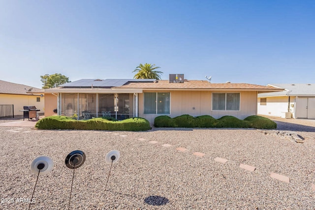 single story home featuring a sunroom and solar panels