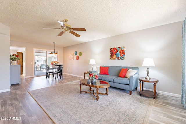 living room with ceiling fan, hardwood / wood-style floors, and a textured ceiling