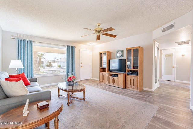 living room featuring ceiling fan, a textured ceiling, and light wood-type flooring