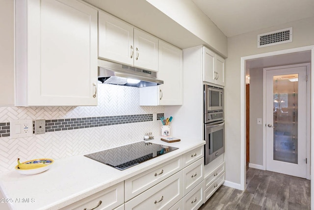 kitchen with backsplash, dark hardwood / wood-style floors, white cabinets, and appliances with stainless steel finishes