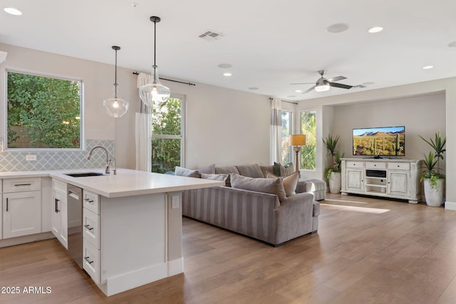 kitchen featuring visible vents, open floor plan, dishwasher, light wood-style floors, and a sink