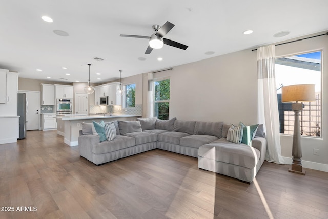 living area featuring visible vents, recessed lighting, baseboards, and wood finished floors