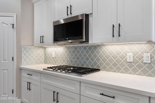 kitchen featuring light stone counters, stainless steel appliances, decorative backsplash, and white cabinetry